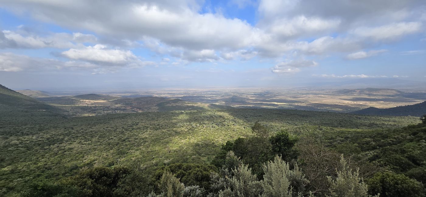 Panoramic Kenyan landscape with rolling green hills under dramatic clouds